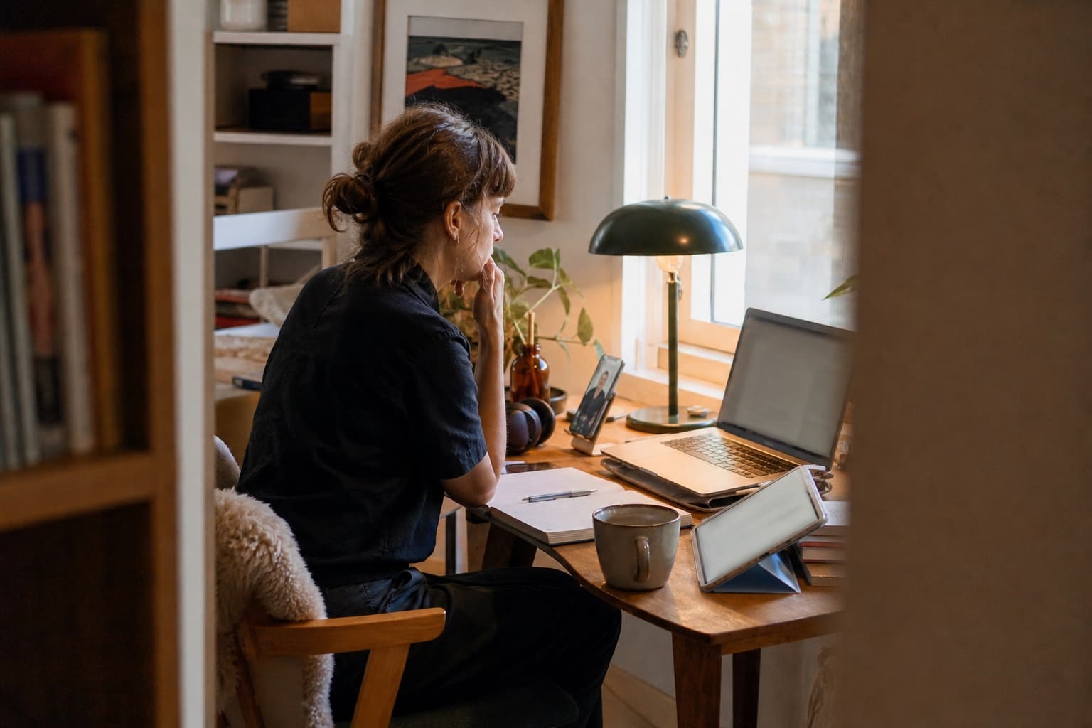 An independent expert works from a small home studio using a laptop, tablet and video call.