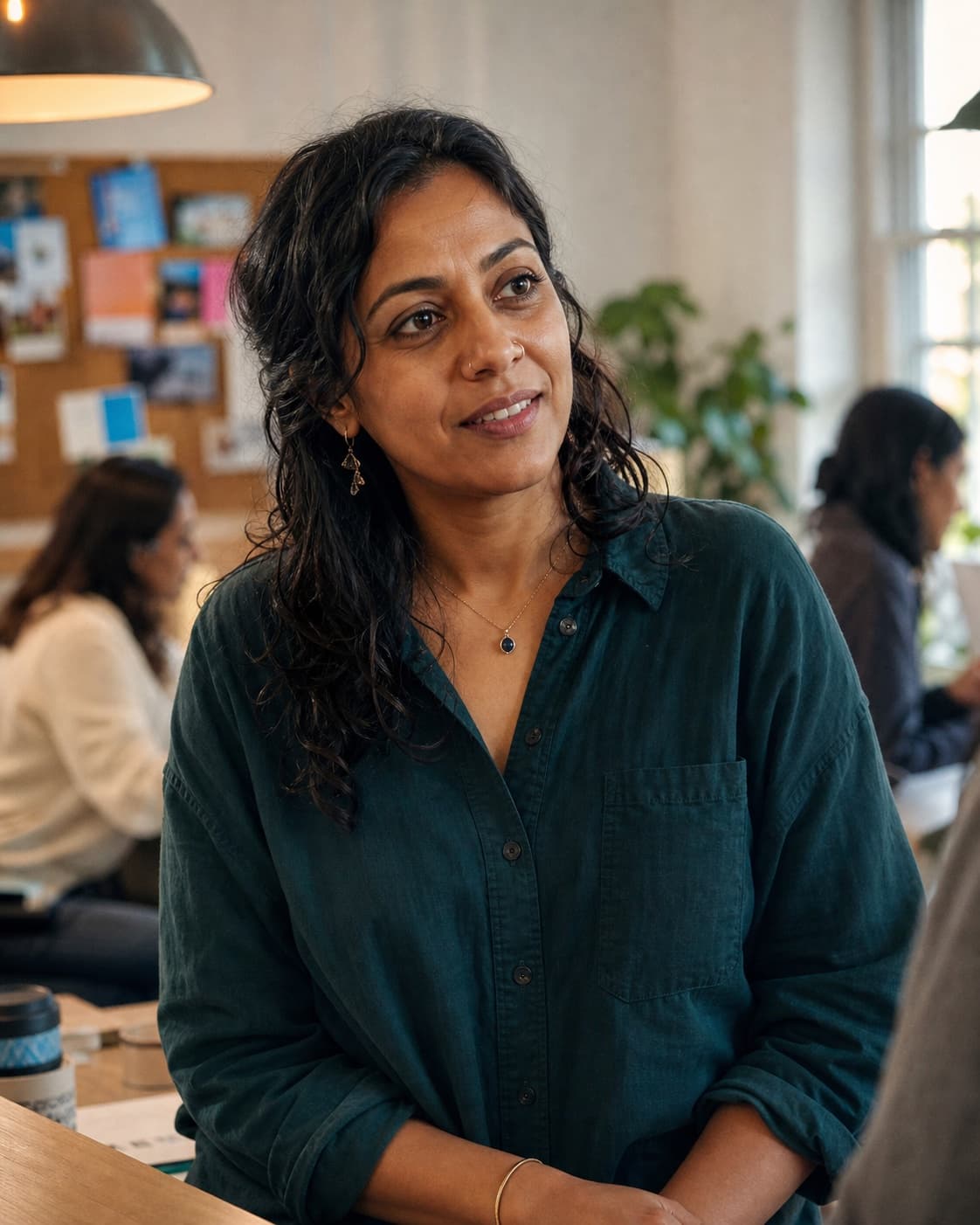 Priya, a charity programme lead, listens to a colleague in a small shared office.