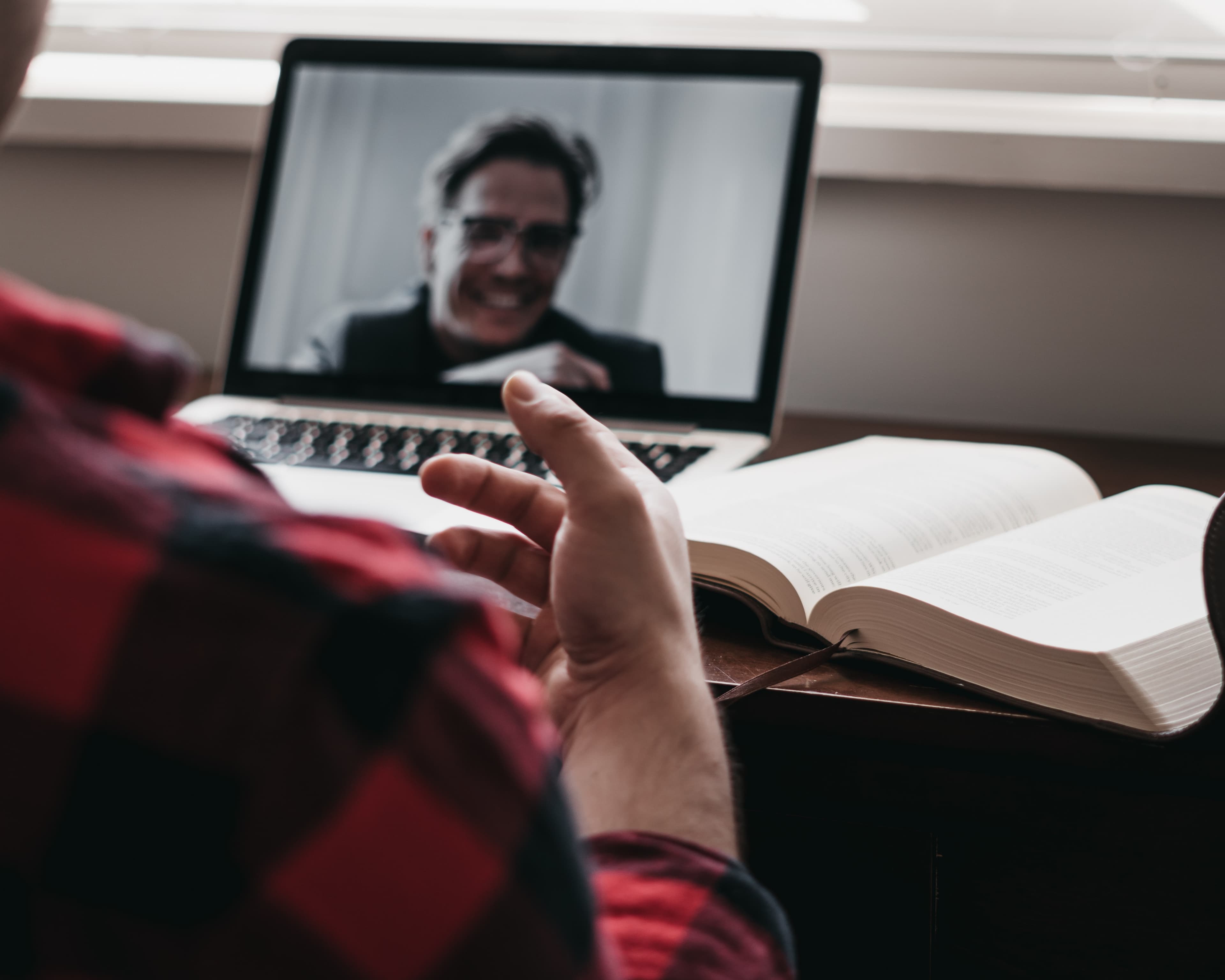 Two people discussing an idea on a video call, with an open book nearby.